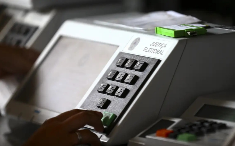 Urna eletrônica branca, com uma digitando um número
