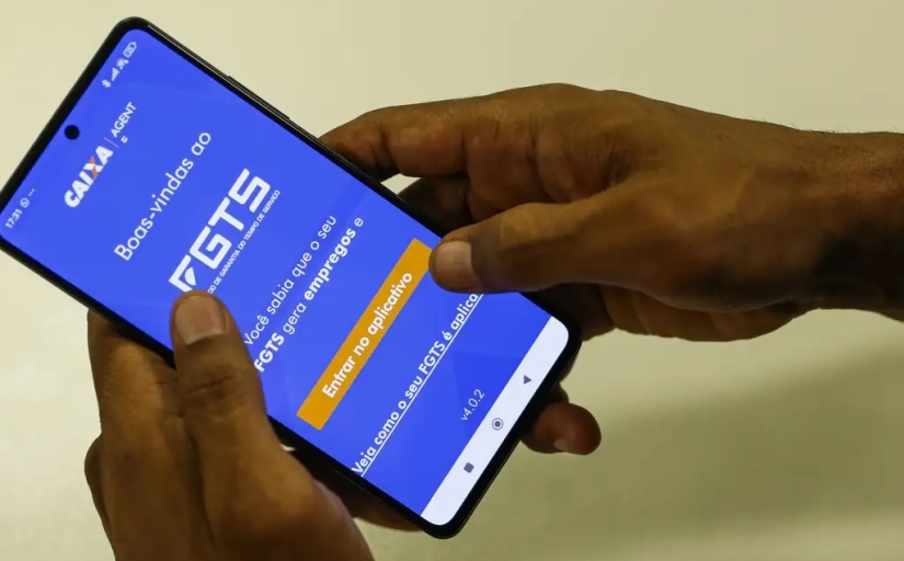 Foto de um smart phone com uma imagem na tela do banco caixa econômica (FGTS)