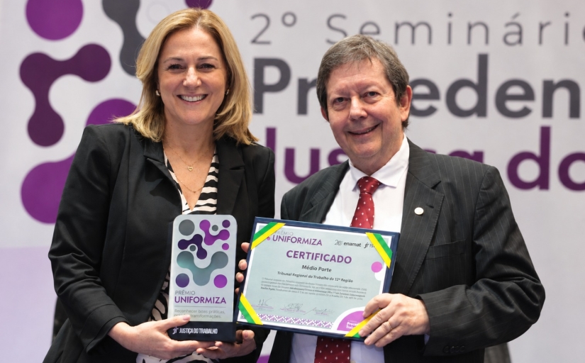 Homem e mulher posam para a foto segurando premiação