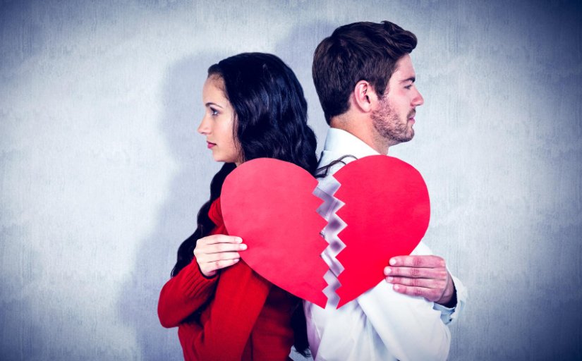 Casal de namorados, um de costas para o outro, segurando uma imagem de um coração rasgado