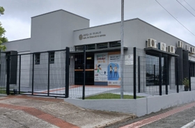 Fachada de edificação de andar térreo com estrutura moderna, pintura em concreto, cerca de proteção e calçada recém-reformada 