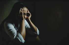 mulher humilhada encolhida em um quarto escuro