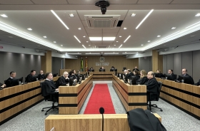 Foto de uma sala de sessões de julgamento composta por magistrados e magistradas de toga