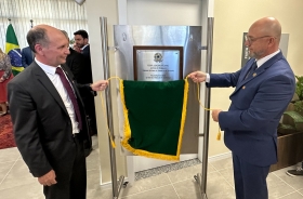 Dois homens de terno e gravata estão descerrando uma placa de inaguração