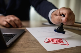 Arte ilustrativa de uma folha de papel sendo carimbada com a palavra "reprovado"