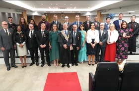 25 pessoas posam para foto em uma sala de sessões de julgamento