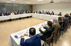 Cerca de 30 autoridades reunidas em uma mesa em formato de U