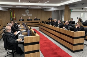 Sala de sessões de um tribunal mostrando 19 pessoas sentadas em uma mesa em formato de U