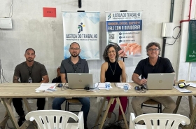 Imagem de uma mulher e três homens sentados em uma mesa com computador