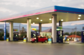 Fotografia ilustrativa com pouca nitidez de um posto de gasolina com movimento durante o dia