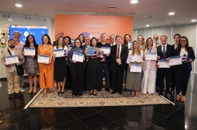 Grupo de cerca de 30 pessoas posam para foto, de pé, exibindo certificados e troféus.