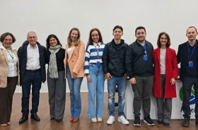 Cinco mulheres e quatro homens estão lado a lado posando para a foto