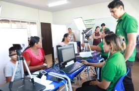 Pessoas participam de um atendimento em uma sala equipada com computadores, câmeras e outros equipamentos tecnológicos.
