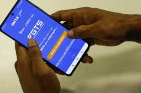 duas mãos segurando um celular, com o aplicativo da "caixa" aberto, tendo o fundo azul, com um letreiro em branco escrito "FGTS"