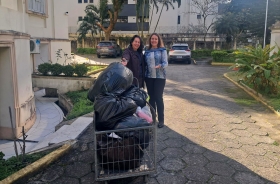 Duas mulheres sorriem para a foto diante de um carrinho cheio de doações