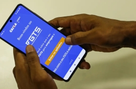 Foto de um smart phone com uma imagem na tela do banco caixa econômica (FGTS)