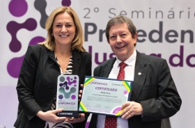 Homem e mulher posam para a foto segurando premiação