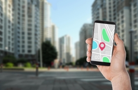Mão segura um celular com a imagem do Google Street View com imagens distorcidas de prédios ao fundo