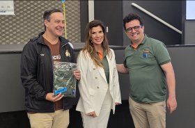 Uma mulher de blazer e calças brancas entre dois homens vestido informalmente