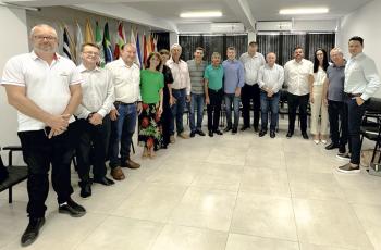 Quatorze pessoas em pé, uma ao lado de outra, de diversas estaturas, formando um semicírculo