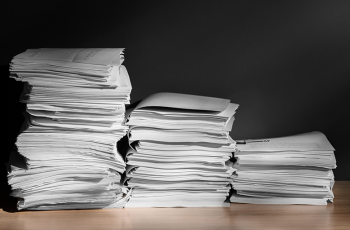 Foto mostra três pilhas de papel sobre uma mesa, organizadas de forma descrescente