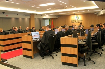 Fotografia da sala de sessões do pleno. Sentados, diante de microfones e telas de computadores, homens e mulheres de toga estão concentrados.