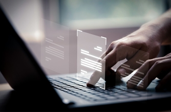 Fotografia ilustrativa de mãos digitando no teclado de um notebook