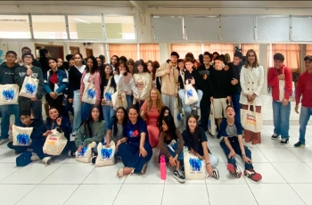 Mais de 40 jovens e três mulheres adultas estão sorrindo e posando para a foto