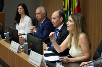 Grupo de quatro pessoas sentadas em uma bancada, como em uma mesa de abertura de evento