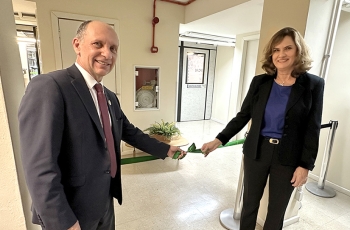 Uma mulher e um homem estão descerrando uma faixa de inauguração