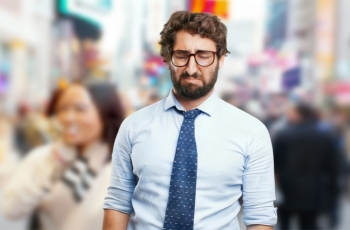 Fotografia ilustrativa de homem jovem em primeiro plano, com expressão chateada