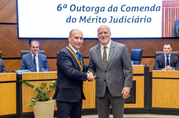 Dois homens de terno se cumprimentam e posam para foto. 