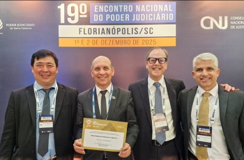 Quatro homens de terno escuro posam para foto. Um deles segura um certificado. 