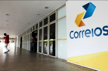 Fotografia da entrada de agência dos Correios com logo grande à direita