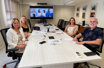 Grupo de pessoas sentadas ao redor de uma mesa branca posam para a foto