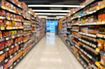 Fotografia ilustrativa de um corredor de supermercado, com os produtos à mostra nas gôndolas