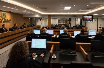Foto de uma reunião no tribunal pleno do TRT-SC com os desembargadores nas mesas com computadores ligados