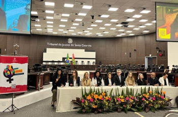 Mesa de autoridades participa de seminário em auditório, com painel do Programa Indira ao lado