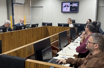 Homens e mulheres sentados ao redor de uma mesa em formato de U