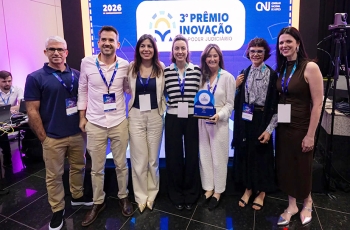 Dois homens e cinco mulher posam para foto segurando premiação