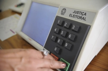 Mão aperta tecla de uma urna eletrônica