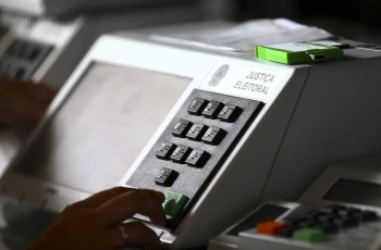 Urna eletrônica branca, com uma digitando um número