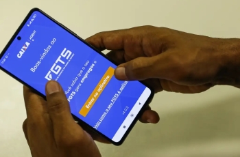 Foto de um smart phone com uma imagem na tela do banco caixa econômica (FGTS)