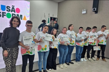 Mulher posa com 10 jovens lado a lado. Todos eles exibem um certificado.
