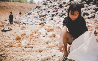 Menina aparentando ser do continente asiático, de cerca de 10 anos, cata resíduos em um lixão 