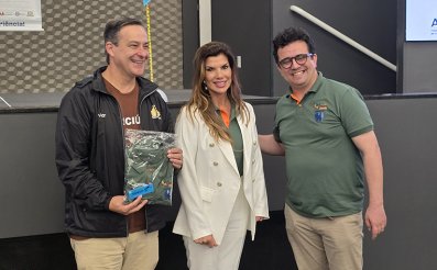 Uma mulher de blazer e calças brancas entre dois homens vestido informalmente