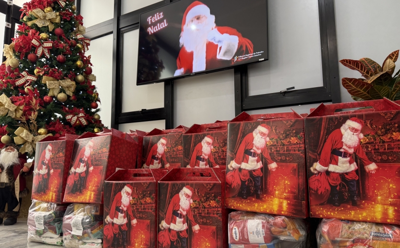 Sequência de caixas com a imagem do Papai Noel. Ao fundo um pinheiro decorado e uma televisão com mensagens natalinas