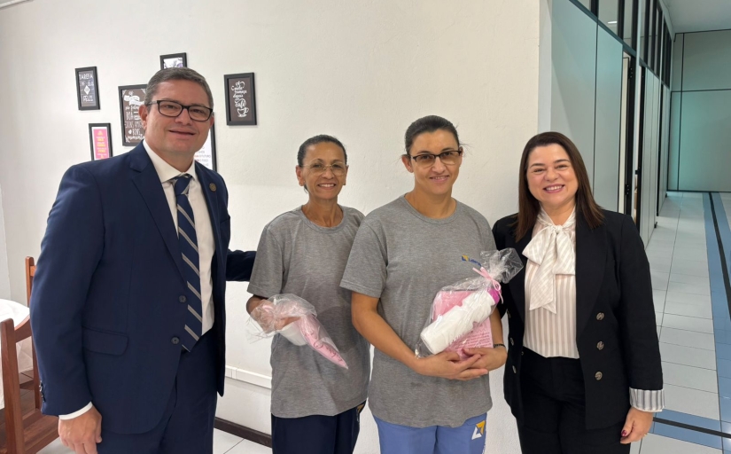 Um homem e três mulheres estão em pé, posando e sorrindo para a foto